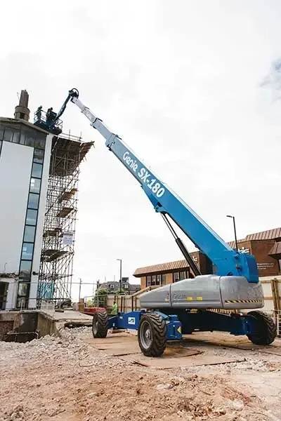 Plataforma elevatória Genie sx 180, sendo vista em operação levantando o operário pro topo de um prédio
